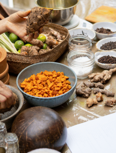 Whole food ingredients and herbs used in holistic nutrition, including turmeric, ginger, spices, and fresh vegetables.