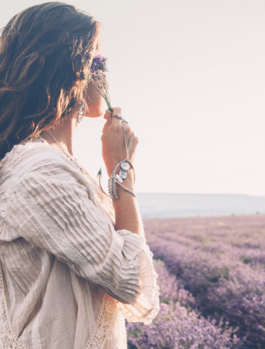 Woman smelling lavender in a field, representing natural wellness and holistic lifestyle.