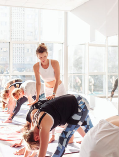 Yoga teacher training workshop with instructor guiding students in functional movement.